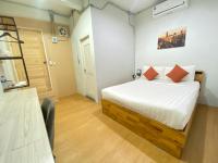素叻ซับรูมโฮเทล Subroom Hotel的卧室里有一张床，床单是白色的，枕头是橙色的