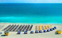 迈阿密海滩Hilton Bentley Miami South Beach的有椅子、遮阳伞和大海的海滩