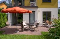 柏林Ferienpark Rübezahl am Müggelsee, Haus 18 Schlehe mit eigener Sauna, idealer Ort für Natur- und Erholungssuchende, für Radfahrer und Familien mit Kindern的露台上的一张桌子、几把椅子和一把遮阳伞