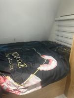 埃拉特קרוואן על הים的一张床，上面铺着黑色的被子，上面写着“hotel”字样