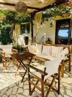 SpartýlasLorantina Luxury Sea View Holiday House close to Barbati &amp; Ipsos Beach with Starlink WiFi的庭院配有白色的椅子和木桌