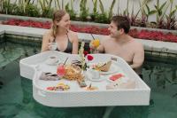 乌布Luxury Nanda villa Ubud的坐在游泳池里吃着饭的男人和女人