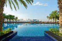 迪拜Rixos The Palm Hotel &amp; Suites - Ultra All Inclusive的一座棕榈树和建筑的大型游泳池