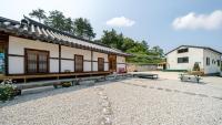 江陵市Gangneung ggabinejip hanok pension的庭院内带桌子和长凳的建筑