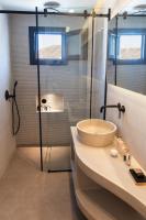 伊亚North Wind Luxury Suites的带水槽和玻璃淋浴间的浴室