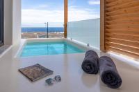 伊亚North Wind Luxury Suites的带小型游泳池的房间，配有太阳镜和毛巾