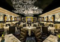 里诺Atlantis Casino Resort Spa的餐厅配有白色的桌椅和吊灯