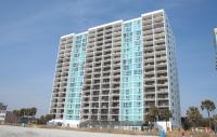 默特尔比奇Club Regency at Regency Towers的海滩上一座高大的建筑,设有蓝色的窗户