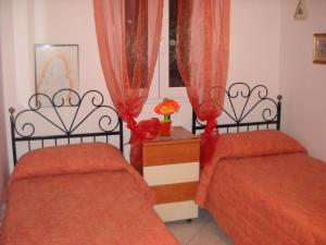 新福卡Villa Anna的配有红色床单和窗帘的客房内的两张床