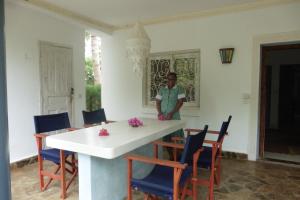 马林迪Downtown Malindi Apartment的站在带桌椅的房间的人