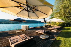 沃尔特湖畔韦尔登西维伦精益酒店的水面上带椅子和遮阳伞的木制甲板