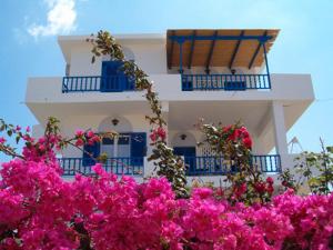 塞里福斯Villa Niki的白色的建筑,设有蓝色的阳台和粉红色的鲜花