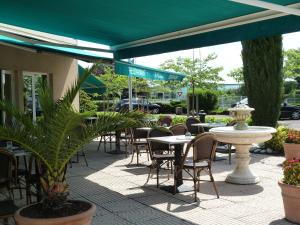 索恩河畔贝尔维尔博若莱的魅力酒店的户外庭院配有桌椅和绿色雨伞。