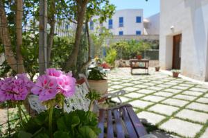 法维尼亚纳Guest House Al Giardino dei Limoni的庭院里设有两把长椅和粉红色的鲜花