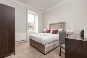 爱丁堡苏格兰迪斯提尼公寓 - 切赫姆亨特套房的白色卧室配有床、书桌和椅子