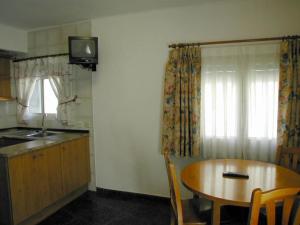 布罗托Apartamentos Gabarre的厨房配有木桌和墙上的电视。