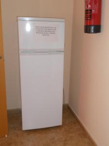 托梅略索桑丘旅馆的一间设有灭火器的房间内的白色冰箱
