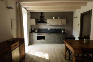 加尔尼亚诺Cascina Varini的厨房配有白色橱柜和木桌
