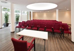 肯普滕圣拉阿尔酒店的一间会议室,配有红色椅子和白色桌子