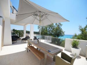 普尔萨诺Luxury Beach Villa Puglia Italy的庭院配有木桌和遮阳伞。