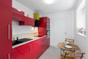 雷恩Corneille by Cocoonr的厨房配有红色橱柜和木桌