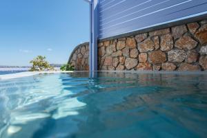 阿克罗蒂里爱阿里诺套房和别墅酒店的石墙旁边的游泳池