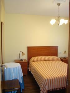 维拉加尔西亚·德·阿劳萨Apartamento Pedras的一间卧室配有两张床、一张桌子和一盏灯。