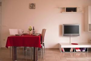 卡利Apartment Suha的一间带红色桌椅和电视的用餐室
