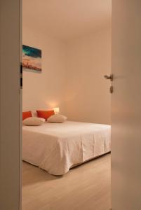 卡利Apartment Suha的一间卧室配有带白色床单和橙色枕头的床。