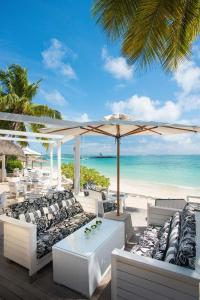 贝尔马尔康斯丹毛里求斯贝尔玛尔度假酒店的海滩上设有白色的椅子和遮阳伞,大海