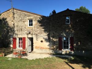 尚托奈Gite Le Puy Rabasteau的一座古老的石头房子,设有红色的门和长凳