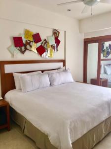 坎昆亲密套房酒店的卧室配有一张白色床,墙上挂着纸牌