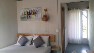 Rodrigues IslandTigraviers Bed & Breakfast的卧室配有带白色枕头的床和窗户。
