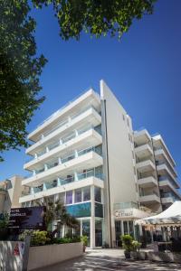 里米尼克里斯塔罗酒店的一座白色的大建筑,前面设有一个游泳池