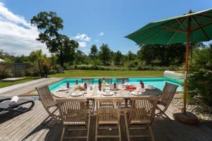 莫列马阿Madame Vacances Villas La Prade的游泳池旁配有桌椅和遮阳伞