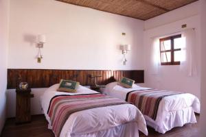 圣佩德罗·德·阿塔卡马蒙特帕尔多旅舍的配有2张床的白色墙壁和窗户。