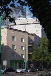 波兹南Szczęśliwa 13的一座高大的建筑,前面有汽车停放