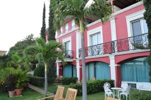 马那瓜Altos de Fontana的一座粉红色的建筑,前面有椅子和棕榈树