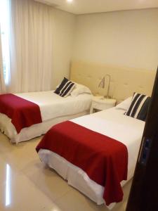 亚松森Realty PY Saravi的酒店客房带两张红色和白色的床单