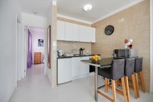 卡门港Knights Apartment的厨房配有白色橱柜和桌椅