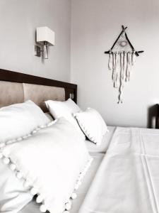 卢特拉艾季普苏Calypso Beach Hotel的一张带白色枕头的床和挂在墙上的时钟