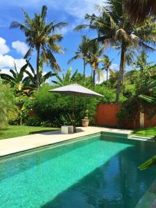 佩母德兰Rhipidura Bungalows by Phocéa的一个带遮阳伞和棕榈树的游泳池
