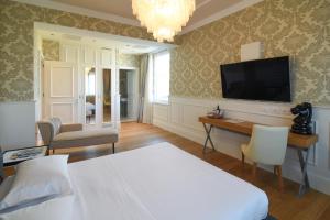 米兰米兰大教堂套房旅馆的一间卧室配有一张床、一张书桌和一台电视