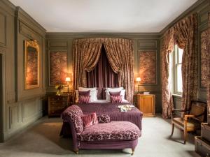 伦敦圣多米尼哥别墅酒店的一间卧室配有一张特大号床和一张紫色沙发