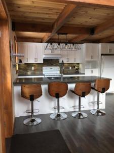 Saint-David-de-FalardeauChalet du Versant Nord的厨房配有带四把吧台凳的吧台