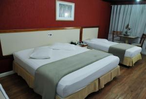 索罗卡巴国际广场酒店的红色墙壁的酒店客房内的两张床