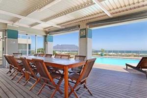 布鲁堡史特兰Beachfront Apartment at Seaspray in Blouberg的一间带桌椅的用餐室和一个游泳池