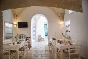 米内尔维诺迪莱切B&B Donnantonietta - Nobile dimora的一间设有白色桌椅和拱门的用餐室