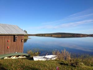 SkauloLakeside House in Lapland的湖畔的房子和两艘船
