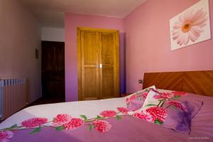 CarcastilloCasa Roblan的一间卧室设有粉红色的墙壁和一张鲜花盛开的床。